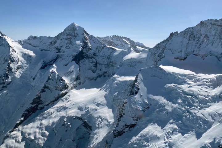 Snow-covered mountain range under clear blue sky.