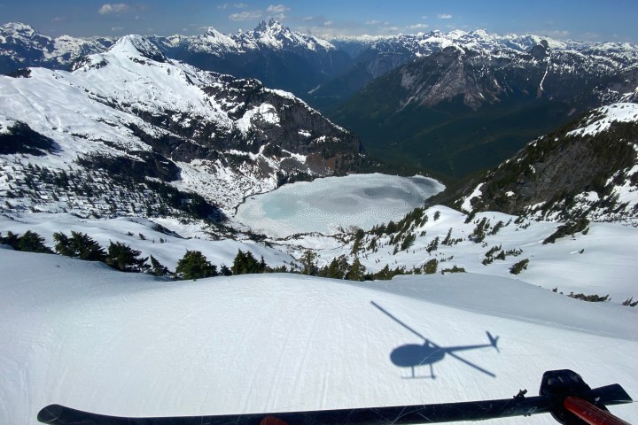 View from a helicopter cockpit flying low over a snow-covered glacier in the mountains before landing during a FunFlights glacier tour.